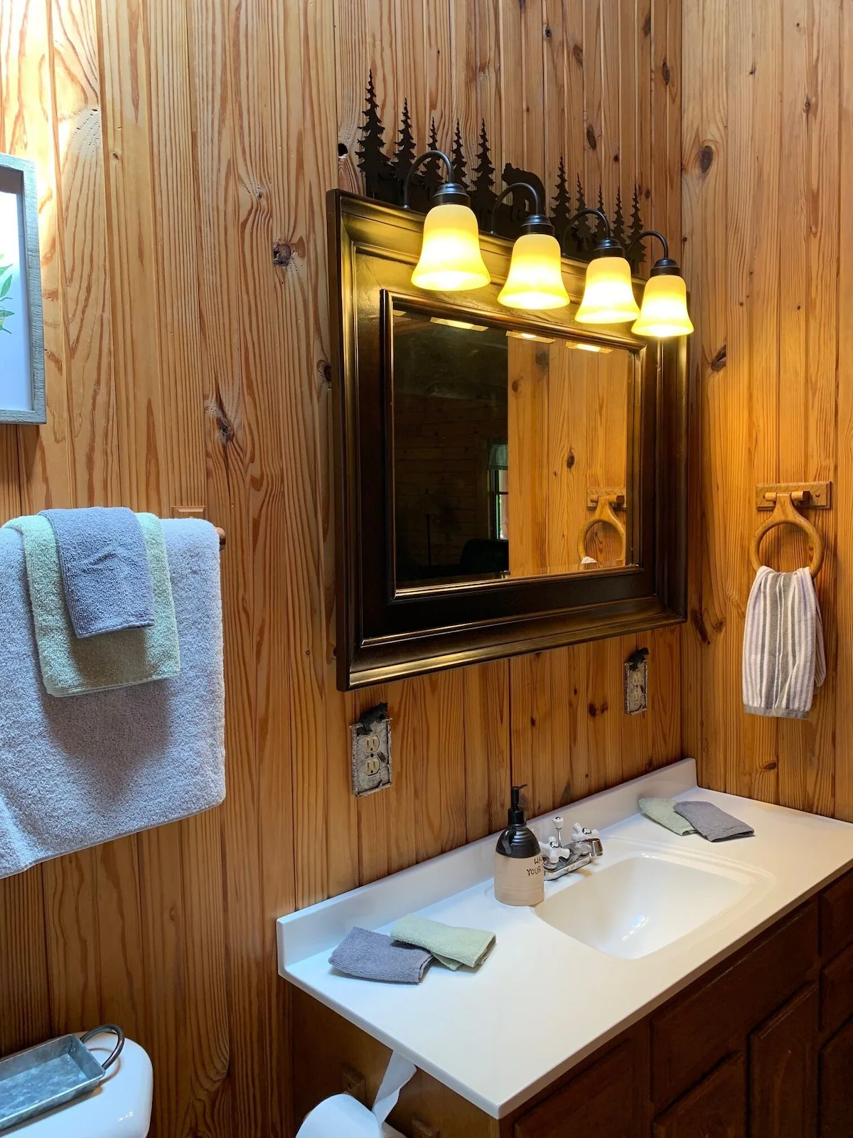 Full bathroom with a wood vanity, framed mirror and folded towels.