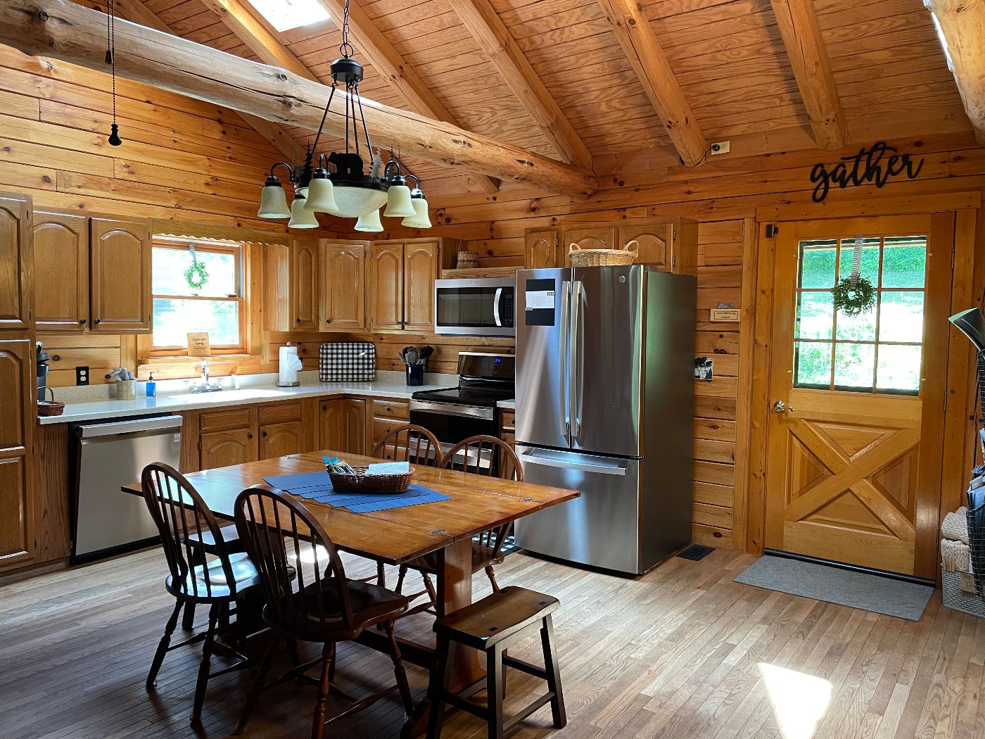 Dining table with placemats and a snack basket in front of the kitchen, refrigerator and range.