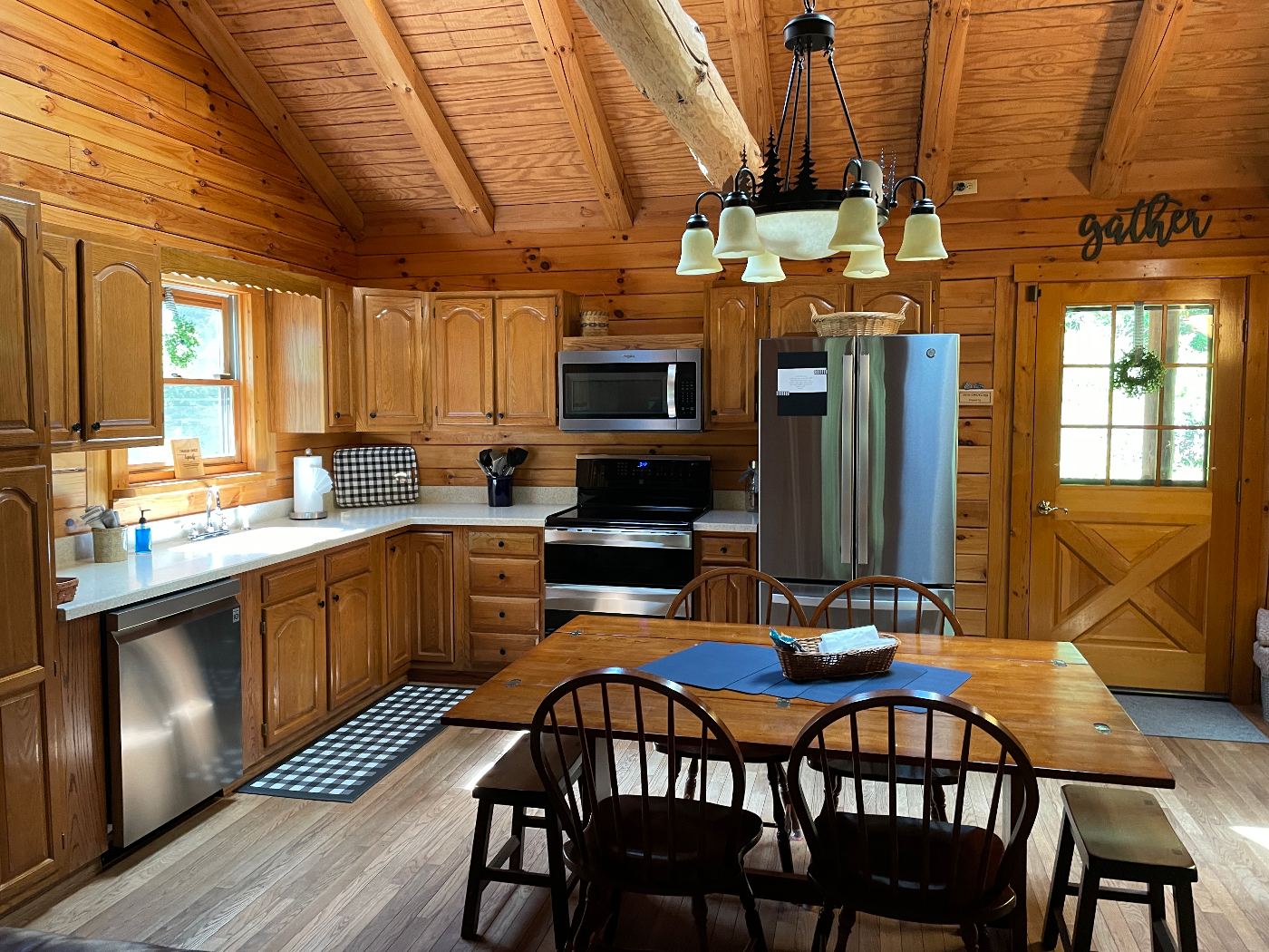 Kitchen with oak cabinets and stainless range under a vaulted beam ceiling.