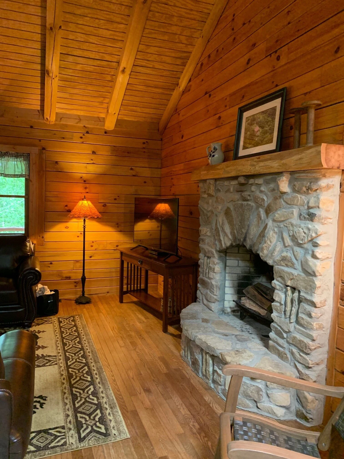 Stone fireplace with a timber mantel beneath a vaulted log ceiling.