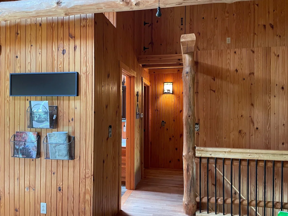Upstairs hallway with guest information baskets and a log post beside the stairs.